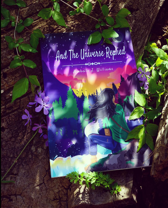 And The Universe Replied Novel Promo Photograph of book laying among leaves and flowers