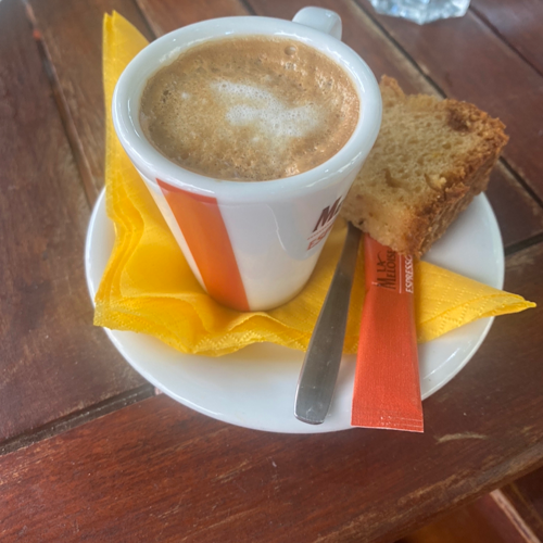 small cup of coffee on a table with an orange napkin