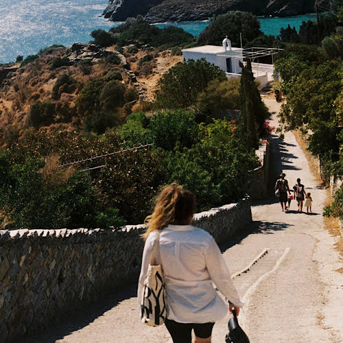 female walking down hill with stairs towards water and church