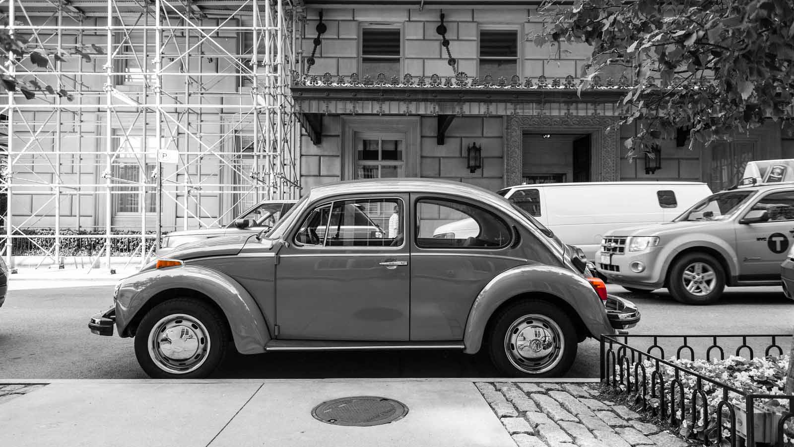 Black and white image with a Volkswagen Beetle in color.