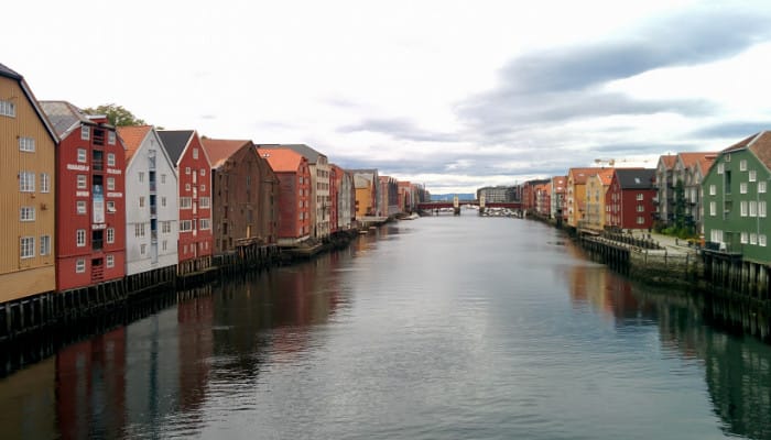 Houses on stilts, against the edge of a river. The houses are wooden and of various colours.