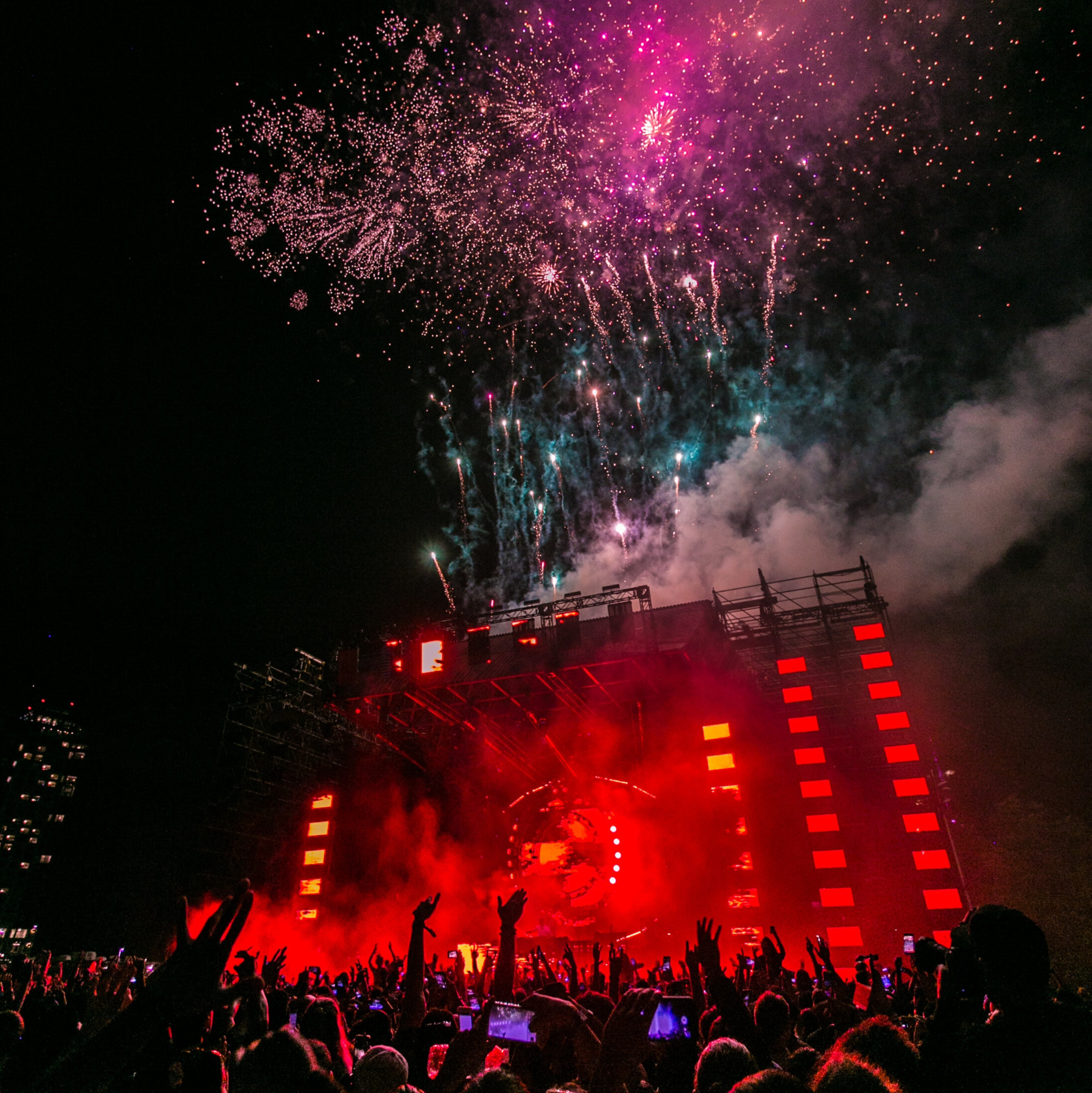 Red stage with fireworks and excited crowd.