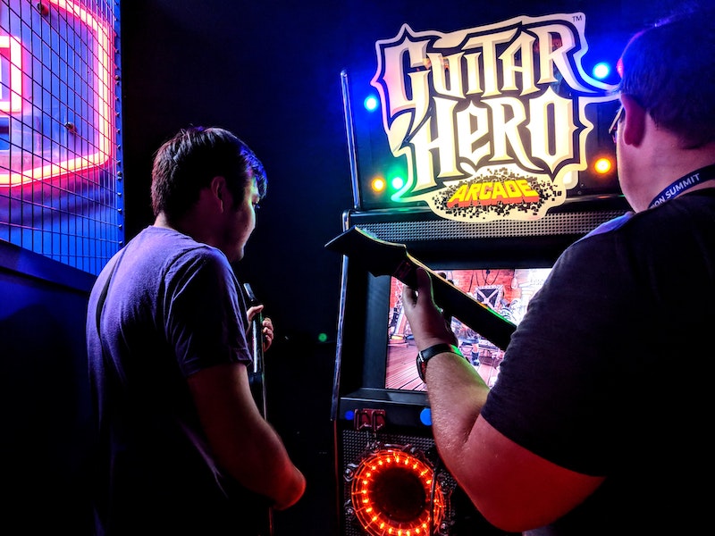 two people playing Guitar Hero Arcade. 