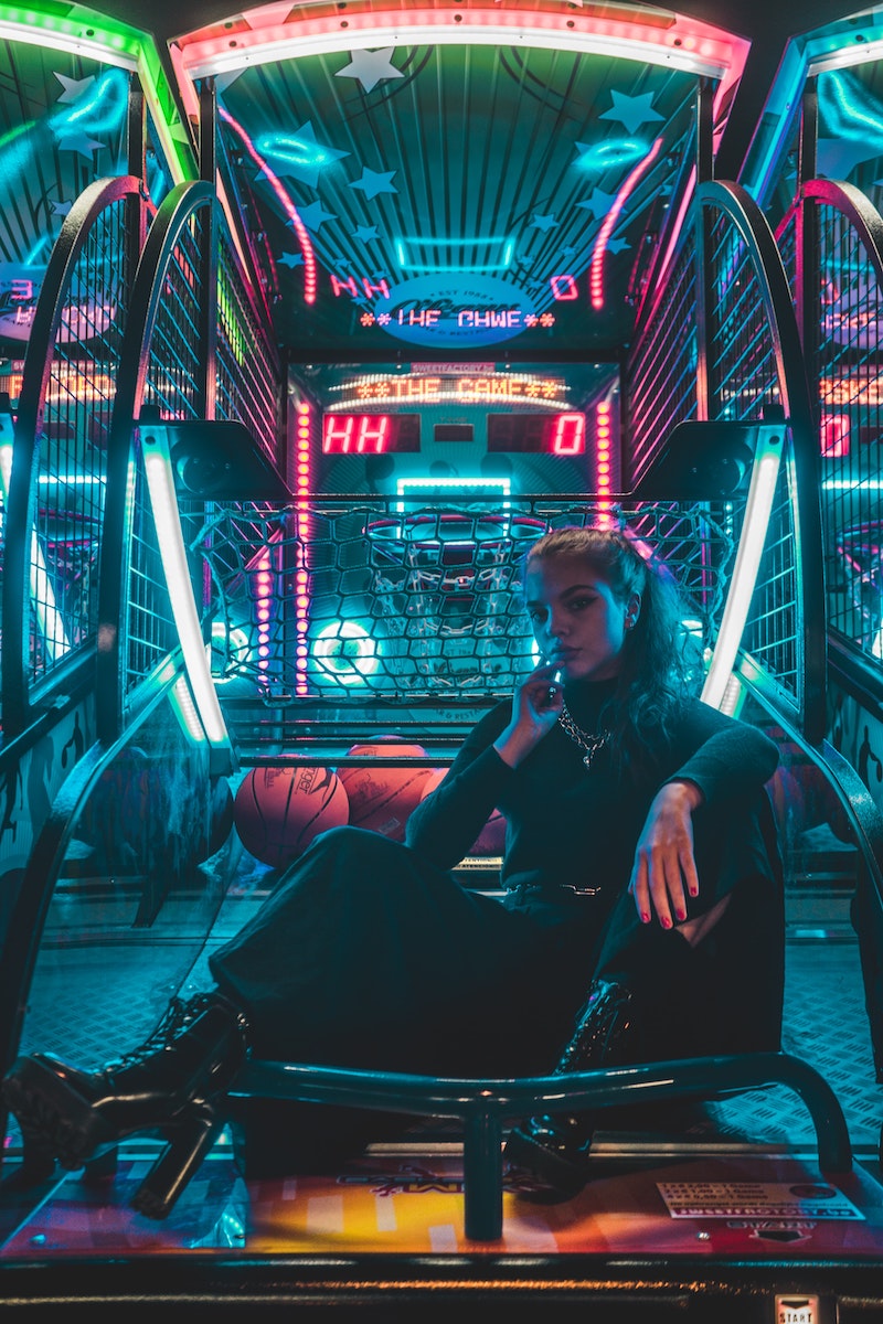 a person in black high-heeled boots sitting on an arcade basketball game. 