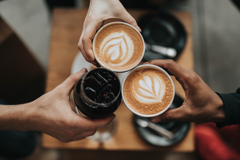 three hands toasting with coffee drinks